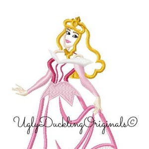 Puede incluir: Diseño bordado de una princesa con un vestido rosa y patines de hielo. La princesa tiene el pelo rubio y una corona. El texto "Ugly Duckling Originals" está en el fondo.