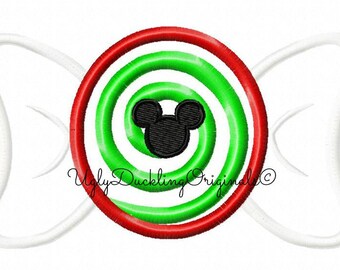 May include: Embroidered candy design featuring a red and green spiral with a black Mickey Mouse head in the center. The candy has white, curved, ribbon-like accents on each side. The text "Ugly Duckling Original" is also present.