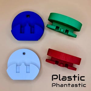 May include: Four colorful plastic objects in blue, green, red, and light blue. The blue and light blue objects are circular with a slot. The green and red objects are rectangular. The text "Plastic Phantastic" is at the bottom.