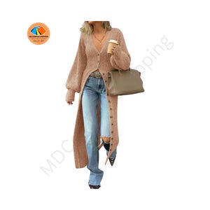 May include: A long, tan, textured knit cardigan with a deep V-neck, long sleeves, and a full-length button-down front. The cardigan is paired with light blue denim jeans featuring a distressed knee and a brown belt with a silver buckle.