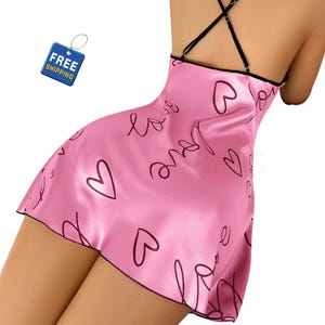 May include: Pink satin slip dress with black trim and spaghetti straps. The dress features a pattern of black hearts and the word "Love" in a handwritten style. The "Free Shipping" tag is visible in the upper left corner.