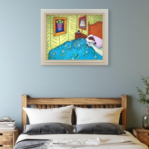 May include: A framed art print depicting a bedroom scene with a dog sleeping under a blue patterned blanket. The room features yellow walls with a green chevron pattern, a wooden headboard, a bedside table with a lamp, and two framed pictures.