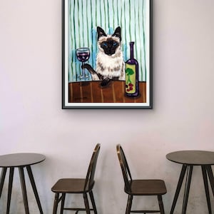 以下が含まれることがあります： 青い目をしたシャム猫がテーブルに座っている額入り絵画。猫は片方の前足で赤ワインのグラスを持ち、その横には緑の木と赤い果実のグラフィックが描かれた紫色のボトルが置かれている。背景は垂直の緑色のストライプ模様。