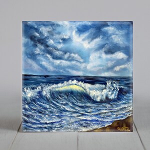 May include: Oil painting of a seascape featuring a breaking wave. The wave is illuminated with a yellow-white light, set against a blue sky with white clouds. The artwork captures the power and beauty of the sea, with a dramatic sky.