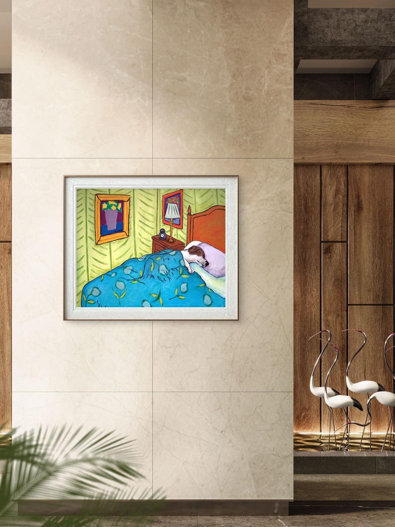 May include: A framed art print depicting a bedroom scene with a dog sleeping in a bed under a blue floral patterned blanket. The room features light green walls, a wooden headboard, a bedside table with a lamp, and two framed pictures on the wall.