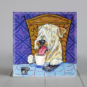 Puede incluir: Una pintura de un perro terrier de trigo de pelo suave sentado en una silla con una taza de café y un teléfono. El perro tiene la lengua fuera y está mirando el teléfono. El fondo es un papel tapiz de patrones morados y azules.