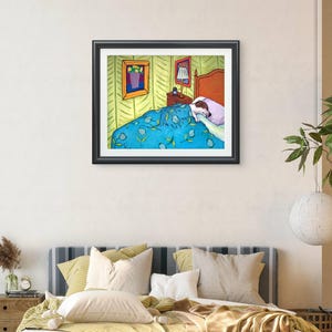 May include: A framed art print depicting a dog sleeping in a bed under a blue blanket with yellow leaf patterns. The bedroom scene includes a bedside table with a lamp, a light-coloured wall, and two framed pictures hanging on the wall above the bed.