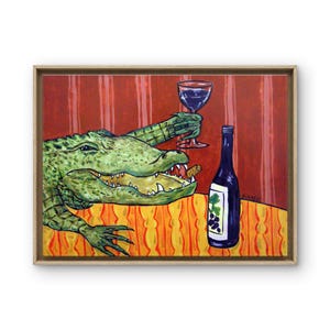 May include: A framed painting depicts a green alligator with an open mouth holding a wine glass in one claw. A dark wine bottle with a grape label sits on an orange and yellow patterned tablecloth. The background features red vertical stripes.