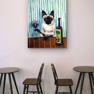 以下が含まれることがあります： 鮮やかな青い目をしたシャム猫が茶色のテーブルに座っている絵画。猫は片方の前足で赤ワインのグラスを持ち、その横には緑の木と赤い果実のグラフィックが描かれた紫色のワインボトルが置かれている。背景は緑色のストライプ模様。