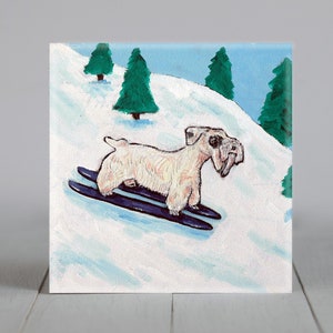 May include: A painting of a dog skiing down a snowy hill. The dog is light tan with dark blue skis. Green trees and a blue sky complete the winter scene. The artwork is on a square canvas.