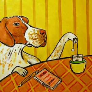 May include: A white and brown dog with a long snout sits at a table with a cup of tea and a notepad that says "TEA" on it. The dog is holding a tea bag with its paw.