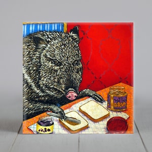 May include: A painting of a brown and black wild pig with a pink snout eating a peanut butter and jelly sandwich. The pig is sitting at a table with a jar of peanut butter and a jar of jelly. The background is red with a blue and white striped pattern.