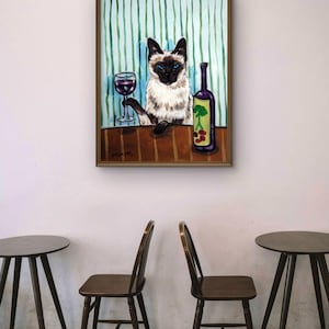 以下が含まれることがあります： 青い目をしたシャム猫が茶色のテーブルに座っている様子を描いた額入り絵画。猫は片方の前足で赤ワインのグラスを持ち、その横には緑の木と赤い果実のグラフィックが描かれた紫色のワインボトルが置かれている。背景は緑色のストライプ模様。
