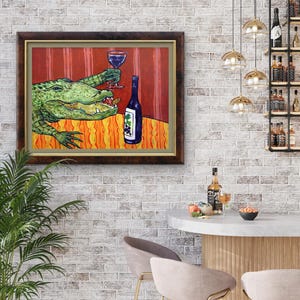 May include: A framed painting depicting a green alligator sitting at a table with an orange patterned tablecloth. The alligator holds a glass of red wine in one claw and has a bottle of wine with a grape label sitting next to it on the table.