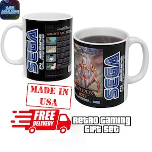 May include: Two white ceramic mugs featuring the Sega Classics Golden Axe video game cover art. One mug displays the game box front with characters, while the other shows the back with game screenshots and text. Both mugs feature the Sega logo.