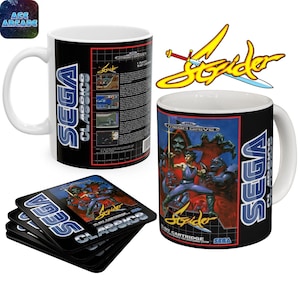 May include: Two white ceramic mugs and a stack of square coasters featuring the Strider video game cover art. The designs include the Sega Classics logo, the Strider title in yellow, and detailed character illustrations from the 16-bit game.