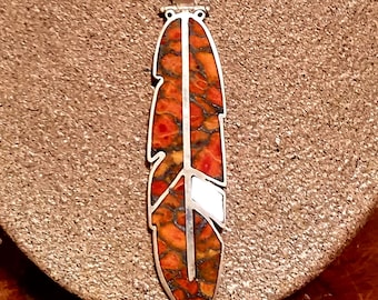 May include: A silver necklace with a red and white feather pendant. The feather is made of a red and white stone with a silver outline.