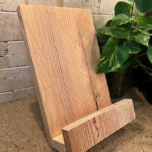 May include: A rustic wooden phone stand or book holder made from reclaimed wood. The stand has a natural wood finish and a simple design.