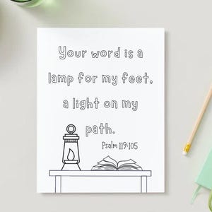 以下が含まれることがあります： 「Your word is a lamp for my feet, a light on my path. Psalm 119:105」のテキストが書かれた白いアートプリント。ランタンと開いた本がテーブルの上に描かれた線画が特徴です。