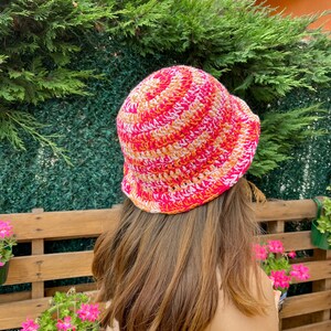 May include: A pink, orange and white striped crochet bucket hat.