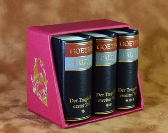 May include: A set of three black leather-bound books with gold lettering. The books are titled "Goethe Faust" and are part of a two-part series. The books are in a red box with a gold design.