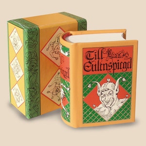 May include: A small, orange book with a green and gold patterned cover. The title of the book is "Till Eulenspiegel" in red lettering.