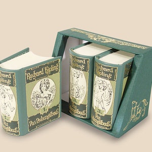 Peut inclure: Un ensemble de trois petits livres verts avec des lettres dorées. Les livres sont intitulés "Rudyard Kipling" et chaque livre a une illustration différente sur la couverture. Les livres sont dans une boîte verte avec une illustration dorée d'un cheval.