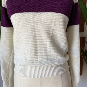 May include: A white and purple striped sweater with long sleeves. The sweater has a ribbed hem and cuffs.