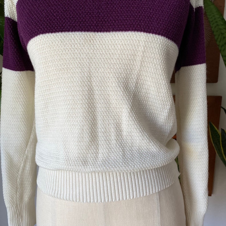 May include: A white and purple striped sweater with long sleeves. The sweater has a ribbed hem and cuffs.