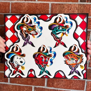 May include: A rectangular art print featuring five cartoon character heads wearing cowboy hats and neckerchiefs. The characters include a rat, a frog, a dog, a red devil, and a cat, all set against a red and white diamond patterned background.