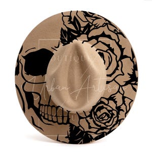 May include: A brown felt fedora hat with a black skull and rose design. The design features a skull with an open mouth and a rose with thorns.