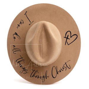 May include: A brown felt fedora hat with the text "I can do all things through Christ" and a cross with a heart around it.