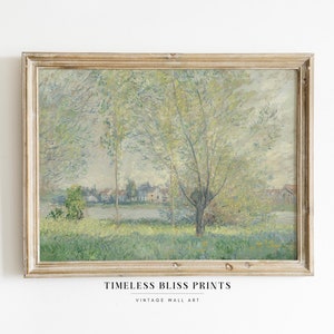 Puede incluir: Una pintura vintage enmarcada que representa un paisaje con un río, árboles y un pueblo en la distancia. La pintura está en un marco de madera claro y tiene una paleta de colores suave y tenue.