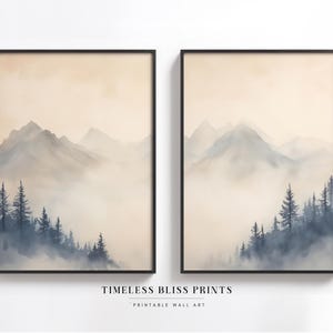 Puede incluir: Dos impresiones enmarcadas de una pintura de acuarela de un paisaje montañoso brumoso con un bosque de árboles en primer plano. Las impresiones están en marcos negros y tienen un fondo beige claro.