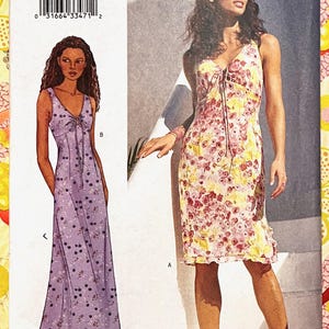 Op de afbeelding: Een Butterick naaipatroon met twee jurk ontwerpen. De ene jurk is een lavendelkleurige maxi met een kersenprint, de andere een bloemen knielange jurk. Het patroon bevat maten 18-22.