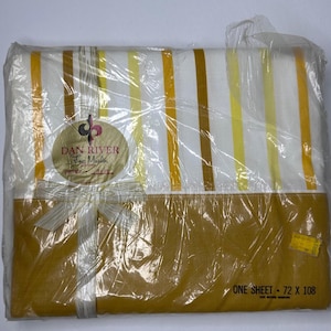 May include: A white sheet with yellow and brown stripes, packaged in plastic. The sheet is labeled "Dan River Fine Muslin" and "One Sheet - 72 x 108".