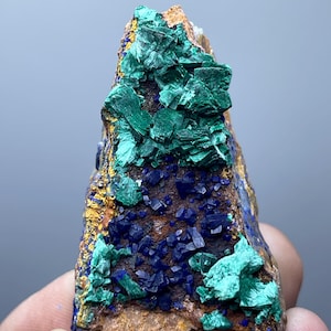 May include: A natural mineral specimen featuring a combination of vibrant colors. The piece showcases deep blue azurite crystals and bright green malachite formations, set against a brown and gold matrix. A unique geological display.
