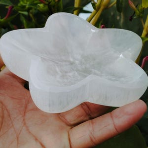 May include: A white selenite star-shaped dish. The dish is made of natural selenite crystal and has a smooth, polished surface.