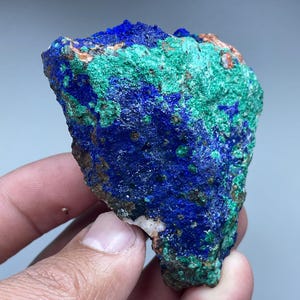 Könnte beinhalten: Ein Azurite- und Malachit-Exemplar mit einem blauen und grünen Farbmuster. Der raue, natürliche Stein hat eine strukturierte Oberfläche.