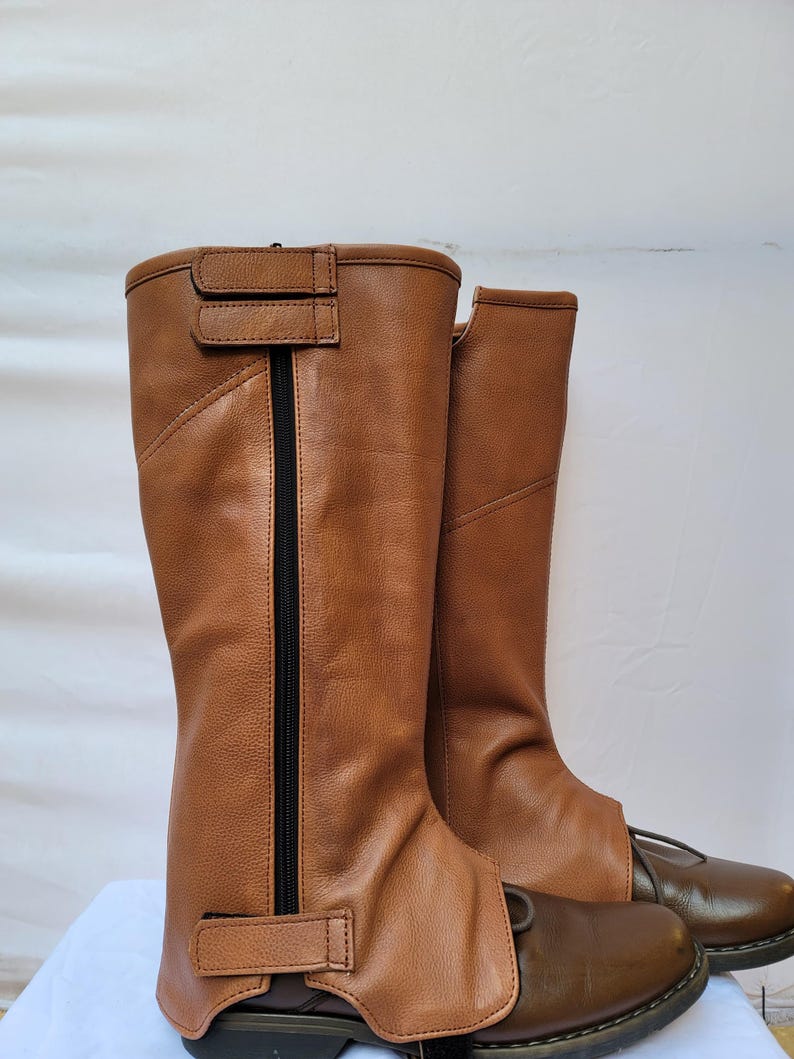 Puede incluir: Un par de botas de montar de cuero marr&oacute;n con una cremallera en el lateral y una correa con hebilla en la parte superior. Las botas est&aacute;n gastadas y tienen un ligero roce en la punta.