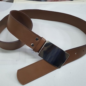 May include: A brown leather belt with a large, rectangular silver buckle. The belt is made of smooth, light brown leather and features a classic design. The buckle is a polished silver color.