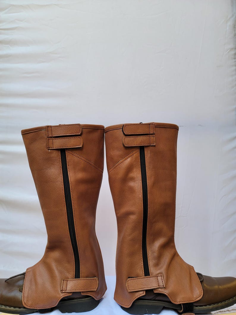 Puede incluir: Un par de botas de montar de cuero marr&oacute;n con cremalleras y hebillas negras. Las botas est&aacute;n hechas de cuero suave y flexible y tienen un ajuste c&oacute;modo.