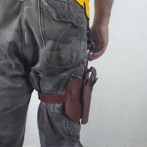 May include: A brown leather holster attached to a leg with a brown strap. The holster is designed to hold a handgun. The person is wearing camouflage pants and a yellow shirt.