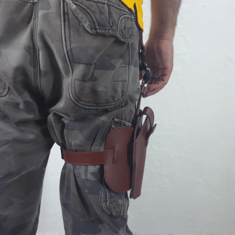 May include: A brown leather holster attached to a leg with a brown strap. The holster is designed to hold a handgun. The person is wearing camouflage pants and a yellow shirt.