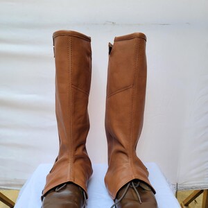 Puede incluir: Un par de polainas de bota de cuero marr&oacute;n con cordones. Las polainas se llevan sobre botas de cuero marr&oacute;n.