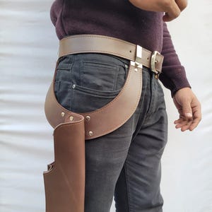 Puede incluir: Juego de cintur&oacute;n y funda de cuero marr&oacute;n. El cintur&oacute;n tiene una hebilla plateada y se usa con una funda marr&oacute;n a juego. La funda est&aacute; unida a una pieza de cuero curvada que se conecta al cintur&oacute;n. El conjunto est&aacute; dise&ntilde;ado para usarse alrededor de la cintura.