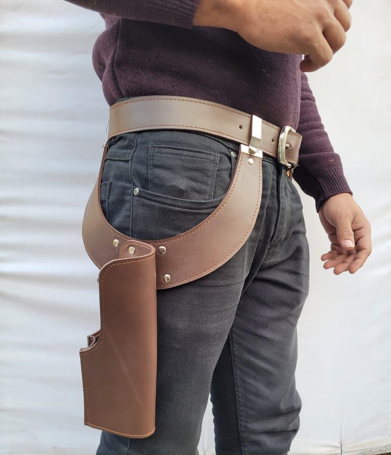 Puede incluir: Juego de cintur&oacute;n y funda de cuero marr&oacute;n. El cintur&oacute;n tiene una hebilla plateada y se usa con una funda marr&oacute;n a juego. La funda est&aacute; unida a una pieza de cuero curvada que se conecta al cintur&oacute;n. El conjunto est&aacute; dise&ntilde;ado para usarse alrededor de la cintura.