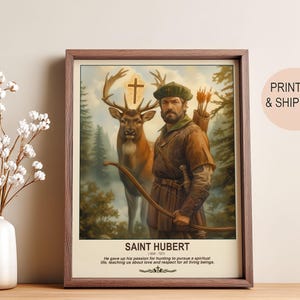 May include: Framed print featuring Saint Hubert, a man in medieval attire with a bow and arrow, standing beside a deer. The artwork includes a cross above the deer and text that reads "SAINT HUBERT" and a quote about love and respect.