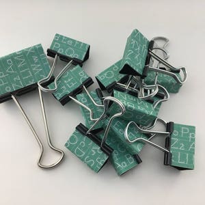 Puede incluir: Un grupo de clips de carpeta con un patr&oacute;n de pizarra verde y letras blancas. Las letras incluyen el alfabeto y las palabras "Po Qg", "Ff Eh", "Li B", "Zz" y "Ppz".
