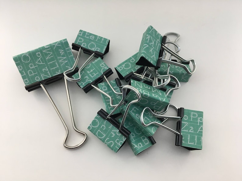 Puede incluir: Un grupo de clips de carpeta con un patr&oacute;n de pizarra verde y letras blancas. Las letras incluyen el alfabeto y las palabras "Po Qg", "Ff Eh", "Li B", "Zz" y "Ppz".